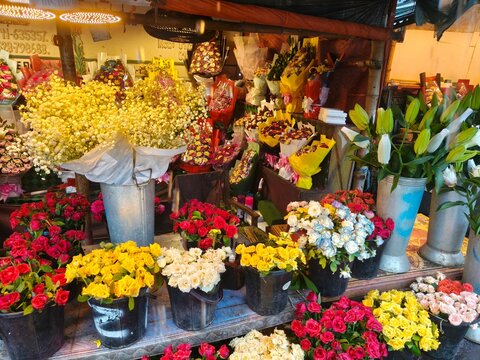 Vibrant flower market display features yellow baby breath bouquets alongside colorful roses in buckets creating lively street retail scene for floral business.