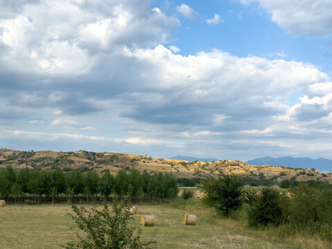 Hay bales scattered across scenic rural farmland landscape