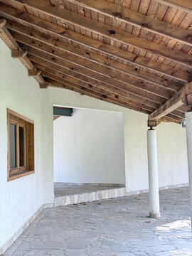 Rustic wooden covered veranda with white plaster walls