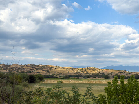 Countryside fields across rolling hills beneath cloudy sky