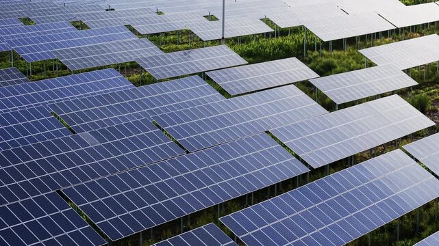 Aerial forward shot of solar panel farm on green landscape, showcasing renewable clean energy, sustainable power, and green technology for ESG and environmental projects.