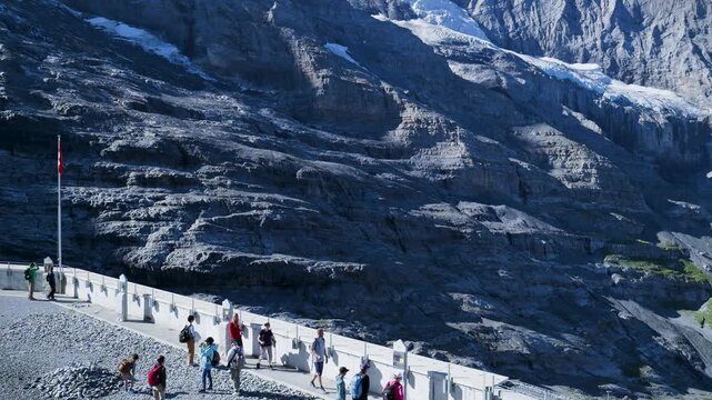 Group of tourists hiking on a trail at the jungfraujoch with the eiger glacier in the background. Switzerland