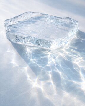 Clear ice block with a unique shape casting reflections on a white surface, showcasing intricate light patterns and textures in a minimalistic setting