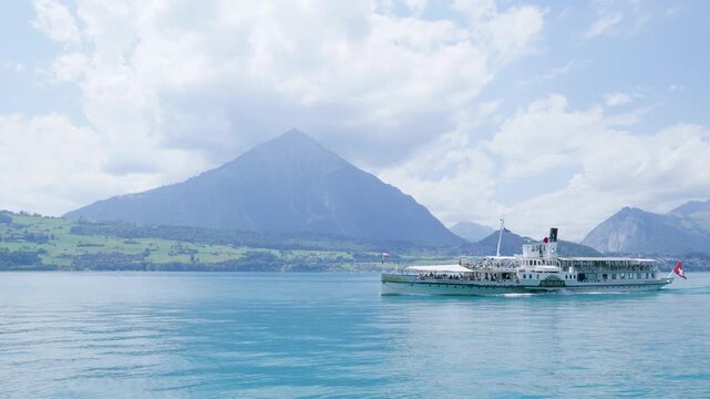 Paddle steamer navigating the turquoise waters of lake thun with the niesen mountain in the background. Switzerland