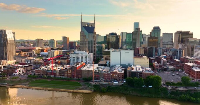 Urban cityscape of Nashville downtown district in Tennessee, USA at sunset. Modern skyline along the river with bridge reflecting city.
