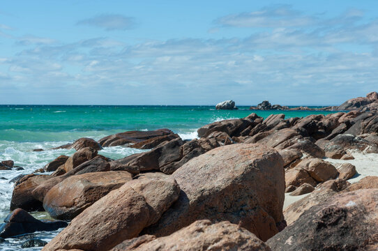 Turquoise waves breaking along a rugged rocky shore