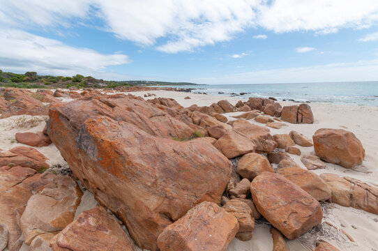 Rocky beach with red granite formations and white sand on the coast of Western Australia