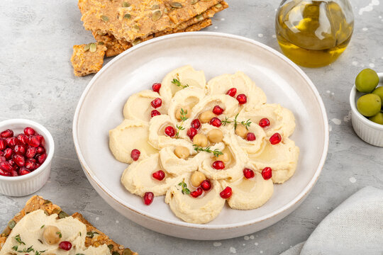 Creamy Hummus Bowl With Pomegranate Seeds, Chickpeas, Olive Oil and Rustic Bread