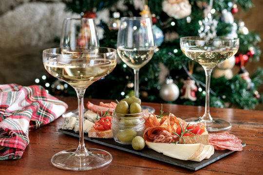 Festive Christmas Charcuterie Board With Wine Glasses Near Decorated Tree For Holiday Gathering