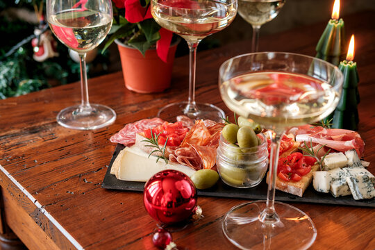 Festive Christmas Charcuterie Board With Wine Glasses Near Decorated Tree For Holiday Gathering