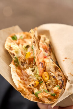 Grilled chicken quesadilla cut open to reveal corn, peppers, lettuce and melted cheese on soft tortilla against neutral background. This is warm, casual meal with rich filling and toasted wrap