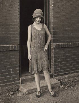 1920s flapper woman posing by brick wall