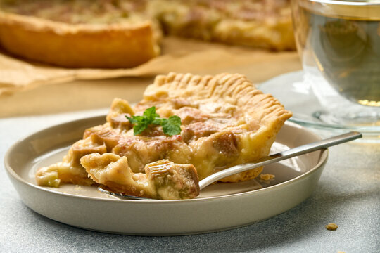 Slice of homemade rhubarb tart on plate with fork and cup in soft natural light, with rhubarb, tart, slice, pie detail, showing pastry, crust, filling, stewed context