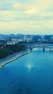 Vertical video. Ufa, Russia. Belsky Bridge spanning the Belaya River, steel half-through arch structure with parallel beam span, aerial panoramic view over the waterway and urban skyline. Drone foota