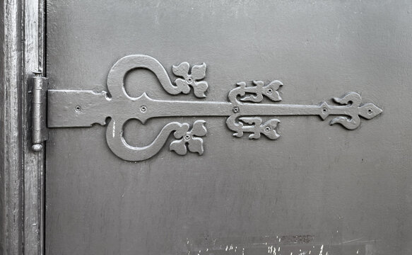 Close-up of ornate old hinge on a weather door