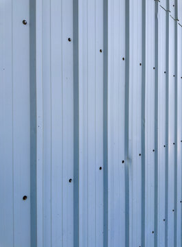 Vertical view along a pale blue steel wall showing perspective