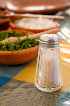Vertical close-up of glass salt shaker on Mexican restaurant table