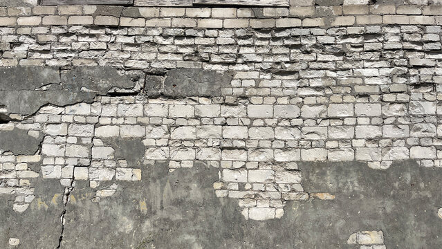 Close‑up of a heavily weathered brick wall with deteriorating plaster, exposed masonry, cracks, and missing sections, creating a rugged urban decay texture with strong architectural character.