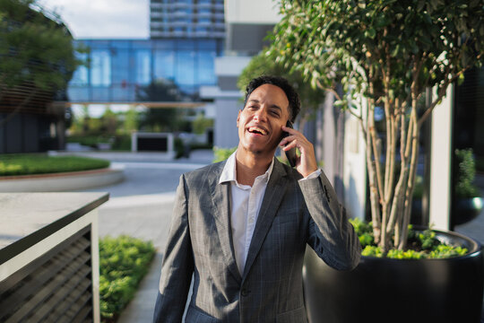 Young businessman walking on street while talking on phone