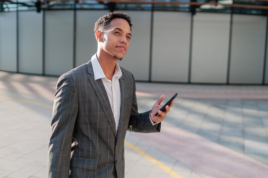 Businessman checks smartphone on street for meeting details during day