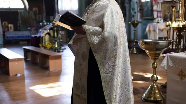 Kiev, Ukraine - August 16 2026: Priest in golden mantle reads Holy Scriptures at service in the church with his palms up. The priest stands at the altar. Holy Mass in the church.