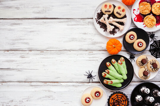 Fun Halloween dessert side border over a white wood background with copy space. Above view. Variety of cookies, cupcakes and pumpkin and apple tarts and pies.