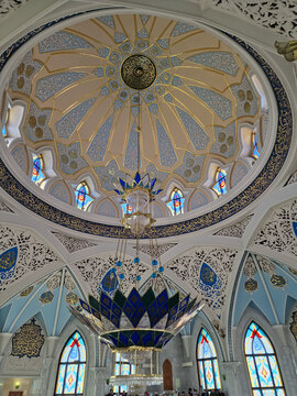 The ceiling vault is a dome with a geometric ornament in beige and blue tones, decorated with gold and Arabic script