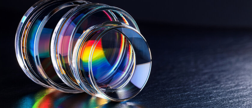 Optical glass lenses with rainbow light spectrum dispersion on dark background