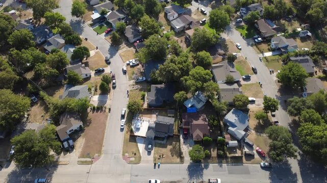 Overhead residential properties cluster along paved avenues across Tarrant County. Single-story rooftops border private driveways dotted with parked motor vehicles, Fort Worth, Texas