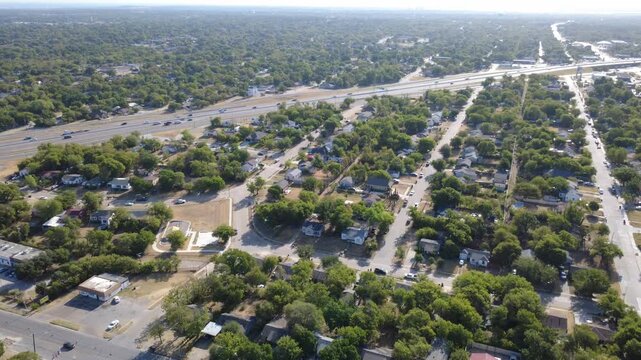 Winding neighborhood roads branch through residential enclaves across Tarrant County. Single-family homes border open recreational grounds beneath bright midday sun, Fort Worth, Texas