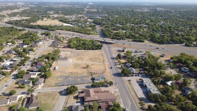 Long thoroughfare pavement follows Mitchell Boulevard across historic Morningside. Open commercial lots flank paved avenues leading toward elevated highway ramps, Fort Worth, Texas