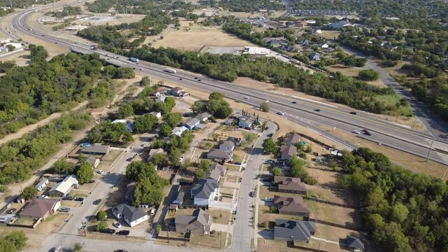 Diagonal expressway lanes along US-287 cross neighborhood streets across Tarrant County. Clustered single-family properties border grassy transportation easements, Fort Worth, Texas