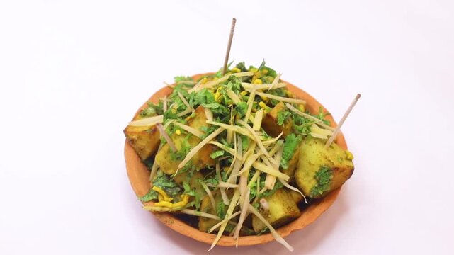 Aalu chaat garnished with ginger slice and coriander on white background
