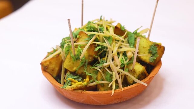 Aalu chaat garnished with ginger slice and coriander on white background