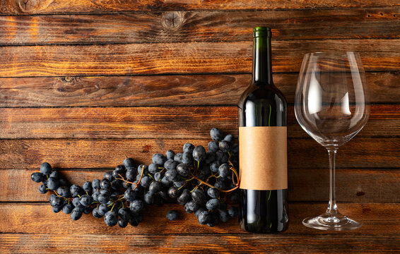 Blue grapes and bottle of red wine on an old wooden table.