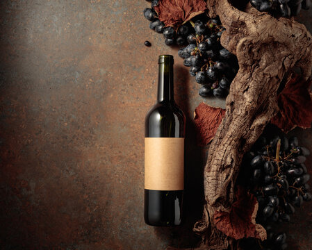 Bottle of red wine with blue grapes on a rusty background.