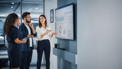 Fototapeta premium Colleague team reviewing business analytics dashboard chart data on wall screen during corporate office meeting discussion together