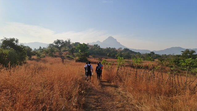 Hikers walking along a mountain trail toward Manikgad Fort in Maharashtra, India
