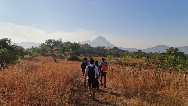 Hikers trekking through dry grassland on the trail to Manikgad Fort in Maharashtra, India