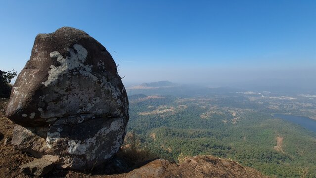 Weathered rock overlooking forested Western Ghats landscape and reservoir in Maharashtra India