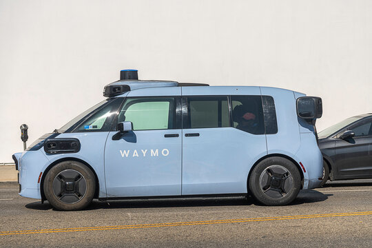Los Angeles, CA, USA: August 22, 2026: A Waymo autonomous taxi drives down La Brea Avenue in Los Angeles, CA. The blue custom-built electronic robotaxi is named the Ojai.