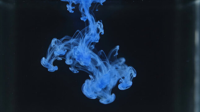 Abstract blue ink plume swirling underwater against a dark background. Fluid motion, creativity, science, mystery, and artistic liquid texture concept with copy space.