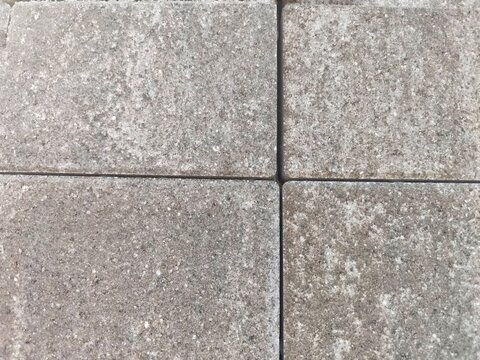 Top down close up of four interlocking grey concrete paving stones with clean joints
