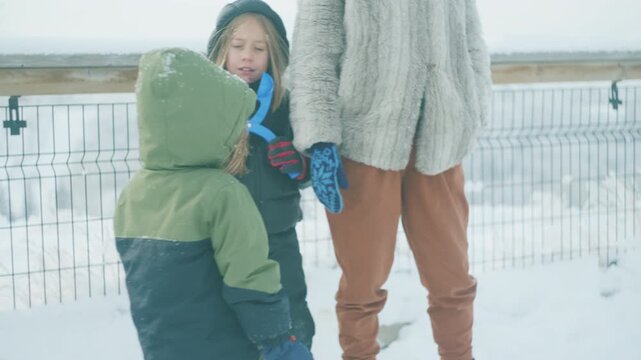 Family walking along a snowy bridge with two boys and their mother on an overcast winter day