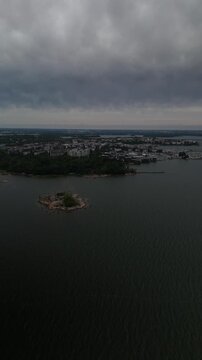 Vertical screen aerial drone view of a coastal city surrounded by Baltic Sea water with islands harbor and urban buildings creating a cinematic Nordic travel landscape from above