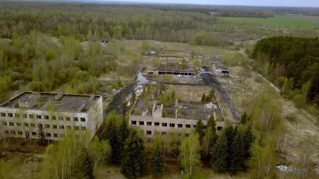 Aerial view of abandoned Soviet military base and ruined concrete buildings surrounded by forest