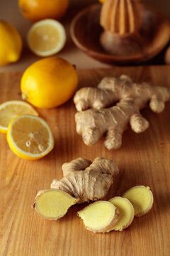 Ginger roots and fresh lemons on a cutting board.