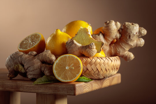 Fresh lemons and organic ginger roots on a wooden board.
