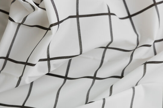 Textured background with a grid pattern created by white fabric with black lines folded and creased