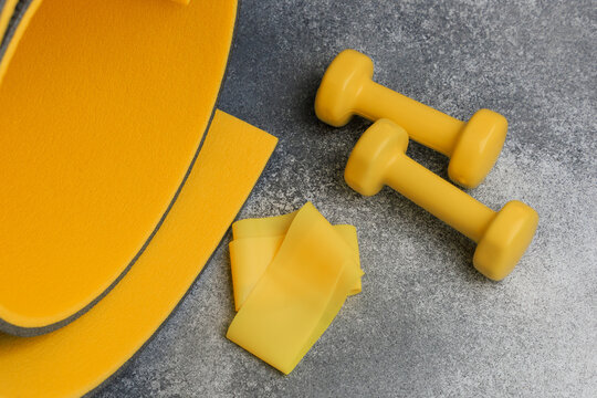 Bright yellow fitness equipment on a grey surface with weights and resistance bands laid out for exercise routines